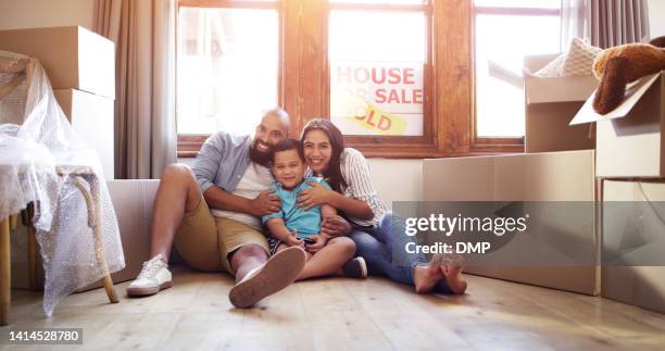 family, moving and new home while happy young parents and their son sit together feeling proud and excited about buying a house. a child, mother and father feeling safe and secured in their house - modelwoning stockfoto's en -beelden