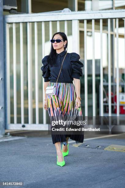 Miki Cheung wears black sunglasses from Prada, a black embossed pattern / puffy shoulder / short sleeves blouse from Munthe, a white matte leather...