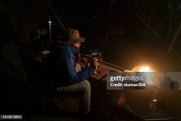 asian camper making bonfire for a warming climate at campsite on the night time outdoor lifestyle - fireplace forest stock pictures, royalty-free photos & images