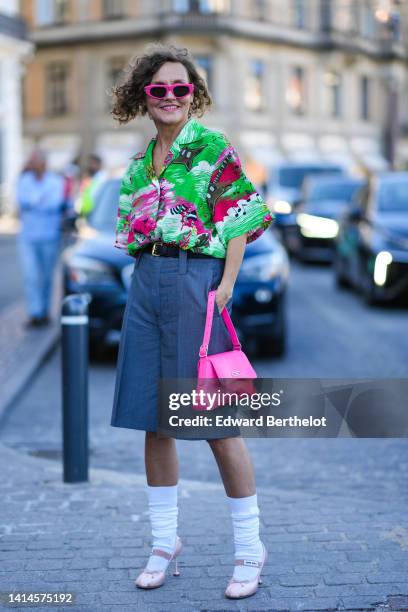 Renata Radzyk wears neon pink sunglasses from Balenciaga, gold earrings, a white with neon green / neon pink print pattern oversized short sleeves...