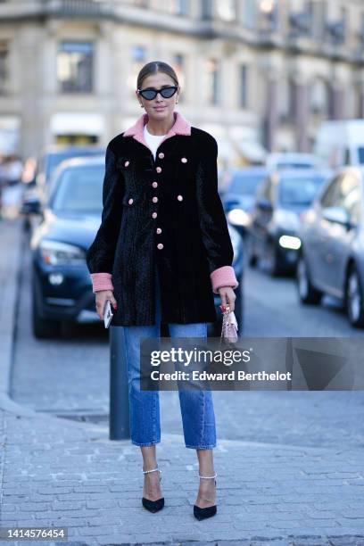 Darja Barannik wears black cat eyes sunglasses, a white t-shirt, a black velvet with pale pink twee collar and buttons jacket, blue faded denim...