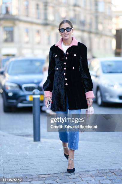 Darja Barannik wears black cat eyes sunglasses, a white t-shirt, a black velvet with pale pink twee collar and buttons jacket, blue faded denim...