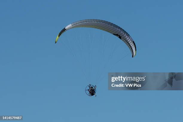Powered paraglider in the air in winter over South Padre Island, Texas. On a powered paraglicer, the pilot wears a backpack motor..