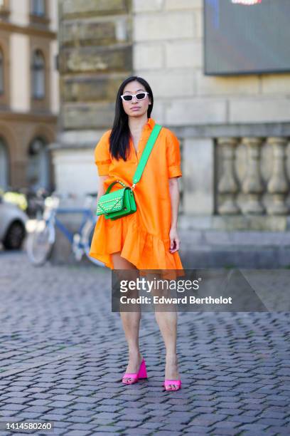 Miki Cheung wears white sunglasses, a neon orange short sleeves / ruffled short dress, a neon green matte leather nailed / studded crossbody bag from...