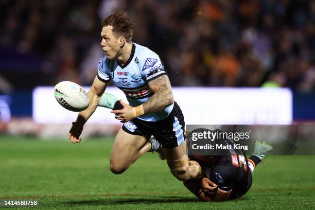 Cameron McInnes of the Sharks offloads the ball in a tackle during the round 22 NRL match between the Wests Tigers and the Cronulla Sharks at Scully...