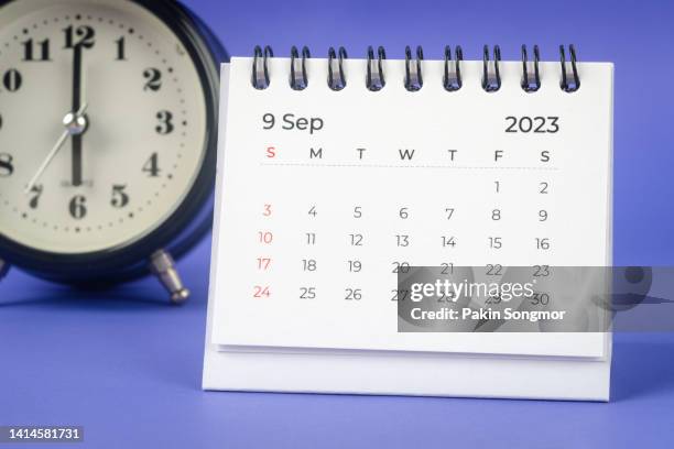 calendar desk 2023 september is the month for the organizer to plan and deadline with an alarm clock on the table against a blue background. - desk calendar stock pictures, royalty-free photos & images