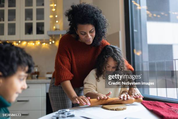 mother making christmas gingerbread cookies with kids - winter cooking stock pictures, royalty-free photos & images