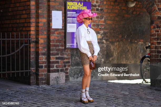 Guest wears a pale pink braided wool with neon pink embroidered fluffy checkered pattern large western hat, black sunglasses, silver earrings, a...