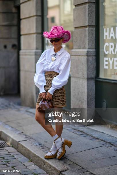 Guest wears a pale pink braided wool with neon pink embroidered fluffy checkered pattern large western hat, black sunglasses, silver earrings, a...