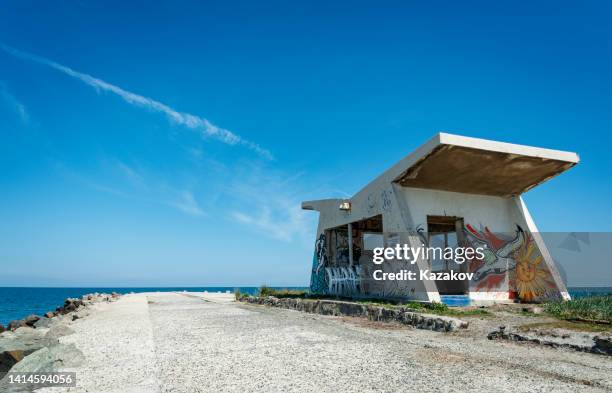 muelle de piedra en la orilla del mar negro en pomorie con edificio con graffiti en él - pomorie fotografías e imágenes de stock