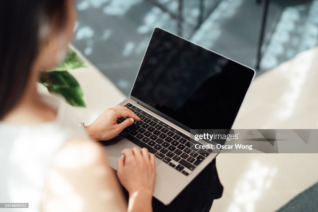 Over the shoulder view of young woman using laptop