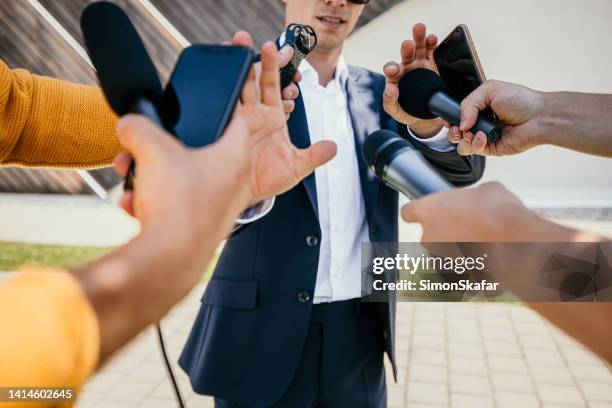 male spokesperson refusing questions while gesturing to journalists in interview - weigeren stockfoto's en -beelden