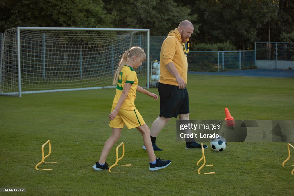 Soccer father and daughter working hard during a coaching session