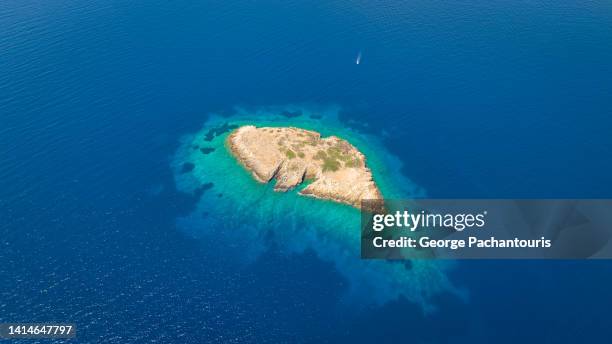 aerial photo of nautical vessel approaching a small island - ägäisches meer stock-fotos und bilder