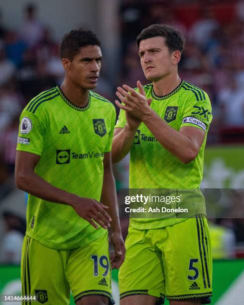 Harry Maguire and Raphael Varane of Manchester United applaud the fans after the Premier League match between Brentford FC and Manchester United at...