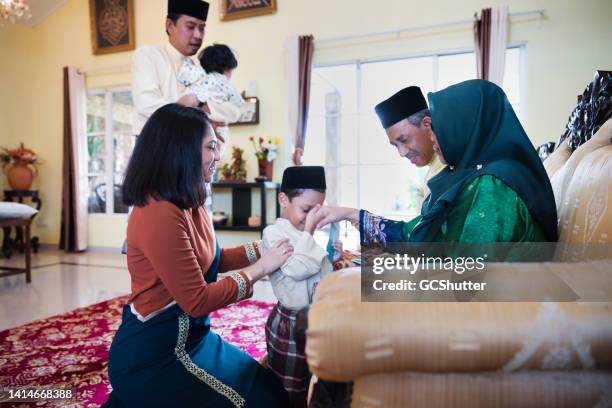 mehrgenerationige malaysische familie feiert hari raya puasa - hari raya celebration stock-fotos und bilder