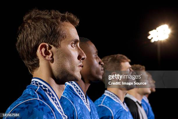 soccer players standing in line on pitch at night - mens soccer team stock pictures, royalty-free photos & images