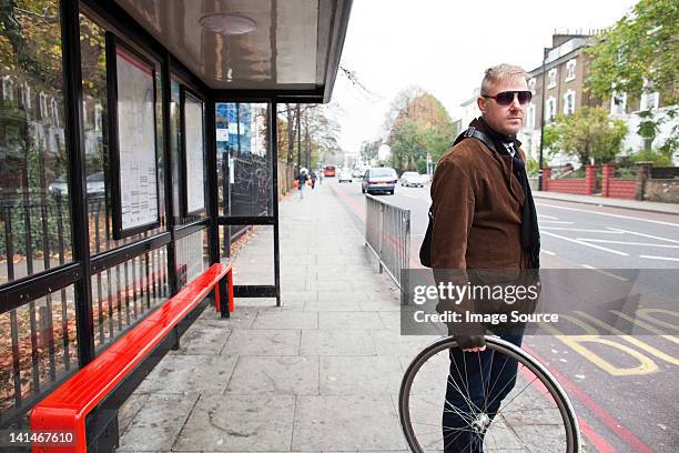 cyclist waiting at bus stop - bus shelter ストックフォトと画像