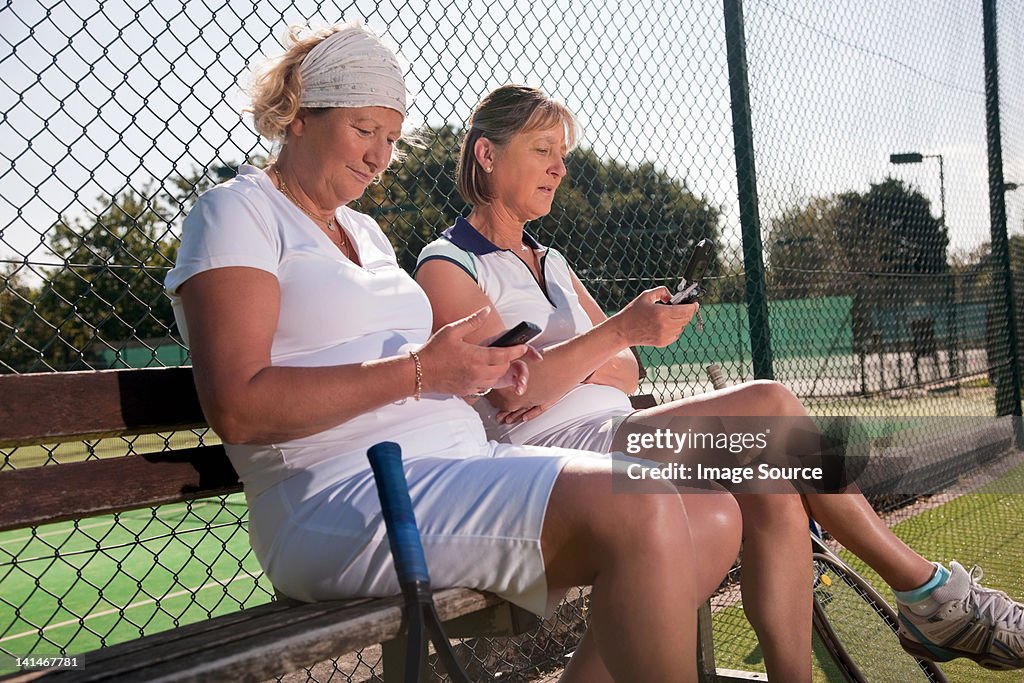 Ältere Frau SMS auf den Tennisplatz