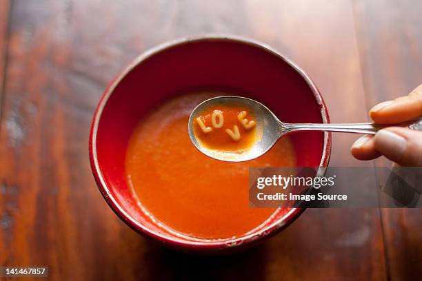 woman holding spoonful of soup with letters love - tomato soup ストックフォトと画像