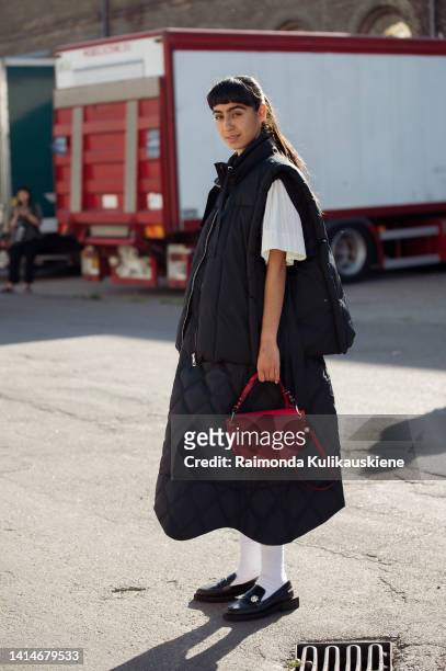 Guest wearing black skirt, white top, black vest, red Ganni bag, white socks and black loafers posing outside Henrik Vibskov during Copenhagen...