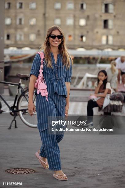 Trine Kjær wearing denim pants and matching shirt, pink bag and slippers posing outside Ganni during Copenhagen Fashion Week Spring/Summer 2023 on...