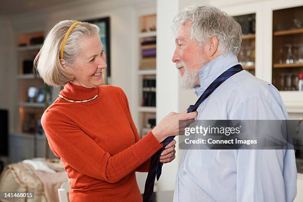 wife tying tie for husband - red polo shirts for men stock pictures, royalty-free photos & images