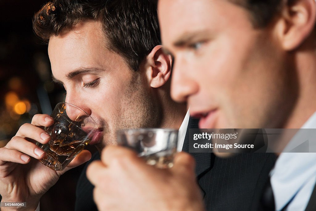 Businessmen drinking shots in bar