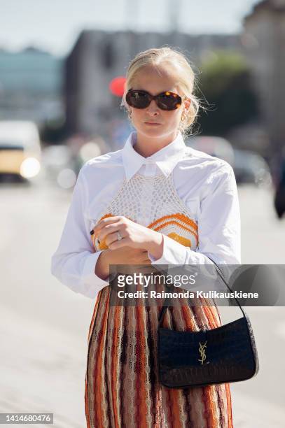 Guest wearing white shirt, long knitted dress, Saint Laurent black bag and beige shoes posing outside Saks Potts during Copenhagen Fashion Week...
