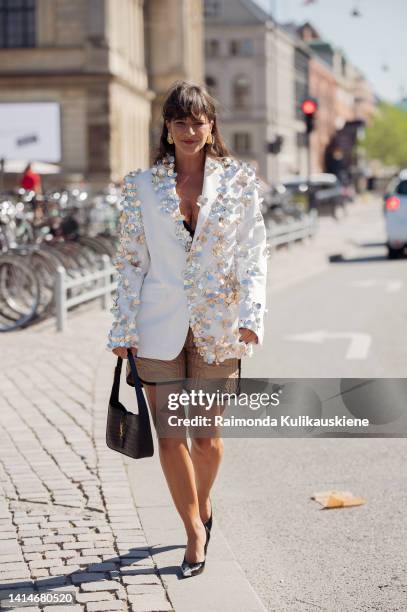 Gili Biegun wearing beige shorts, white oversized jacket with metal flower decorations and black Saint Laurent bag posing outside Saks Potts during...