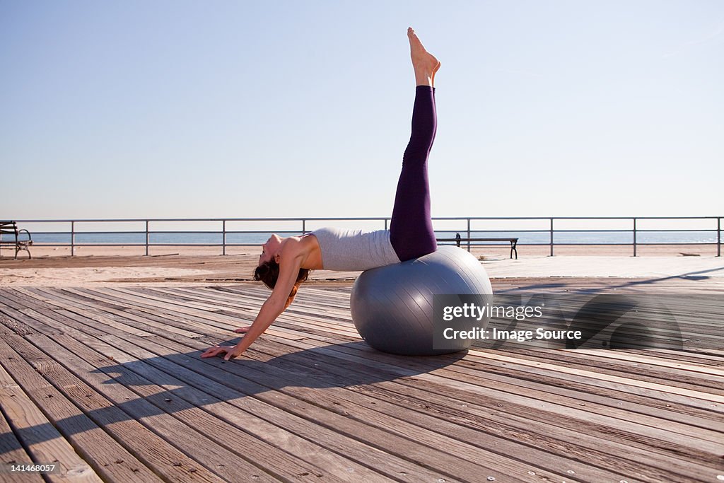 Woman stretching on exercise ball on promenade