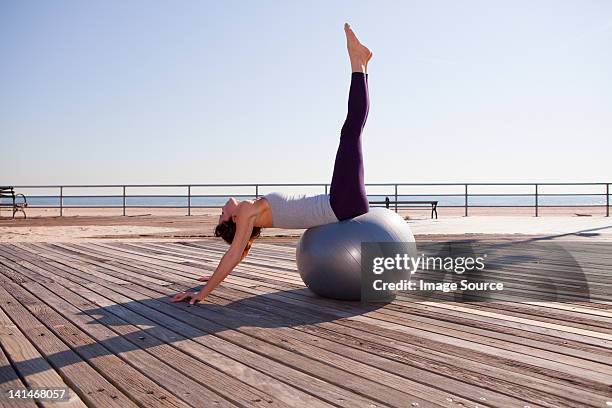 woman stretching on exercise ball on promenade - legs crossed at knee stock pictures, royalty-free photos & images