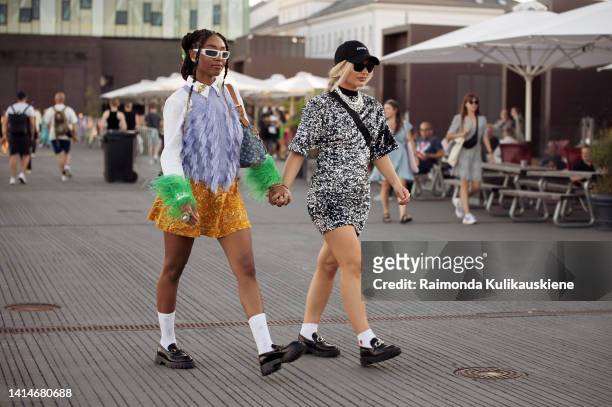 Petra Henriette Rufi wearing white shirt with green fur, lilac vest, yellow skirt, white socks, black loafers and Maria Wos wearing glitter black and...