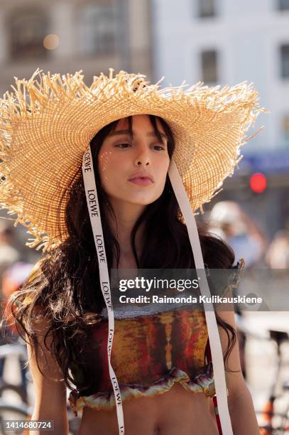 Livia Nunes Marques wearing Loewe sun hat long colourful yellow and green and blue and red knitted skirt with a cowboy style leather belt with metal...