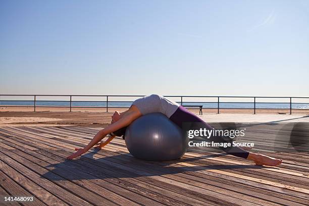 woman lying over exercise ball on promenade - fitness ball stock pictures, royalty-free photos & images