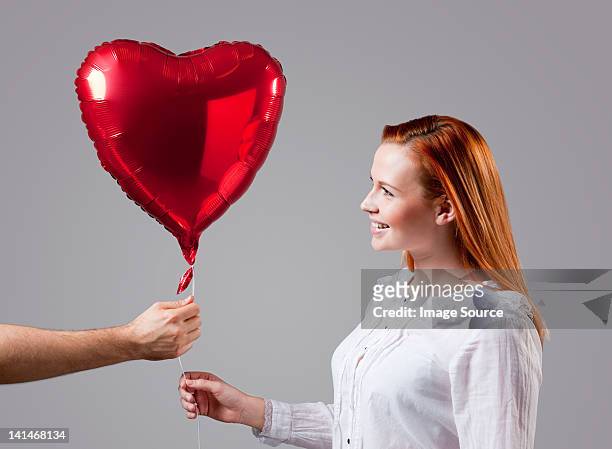young woman being given heart shaped balloon - man blouse stock pictures, royalty-free photos & images