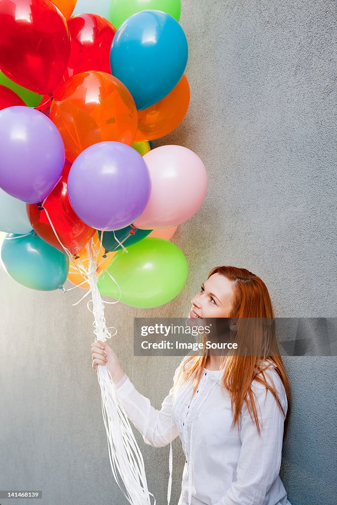 Junge Frau mit Haufen bunte Ballons