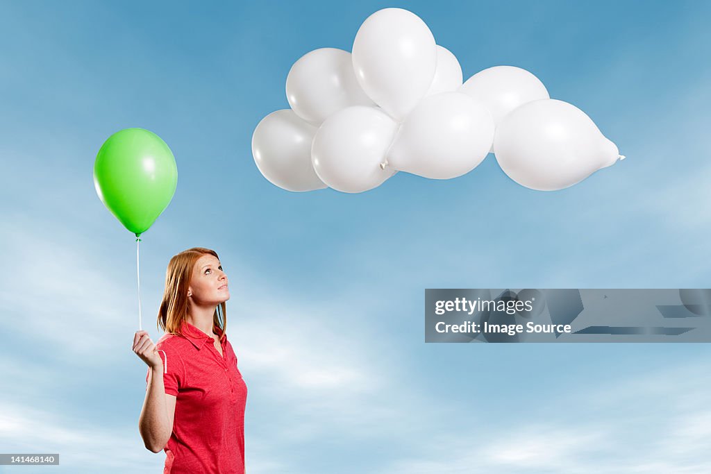 Giovane donna guardando cloud fatto di palloncini