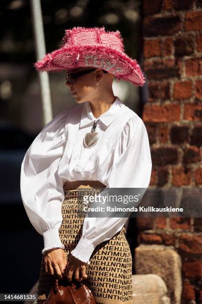 Emma Fridsell wearing white shirt, beige Munthe mini skirt, grey socks and block heel shoes, brown bag and pink and red cowboy hat posing outside...