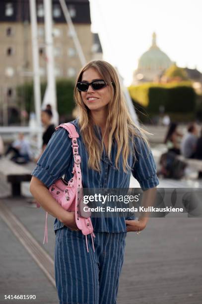 Trine Kjær wearing denim pants and matching shirt, pink bag and slippers posing outside Ganni during Copenhagen Fashion Week Spring/Summer 2023 on...