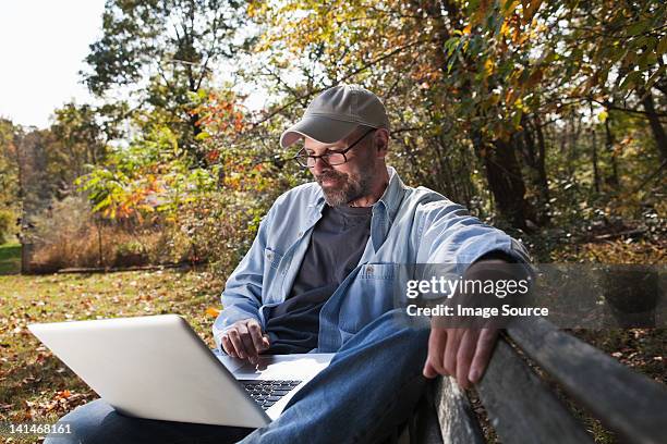 mature man using laptop outdoors - season 42 stock pictures, royalty-free photos & images