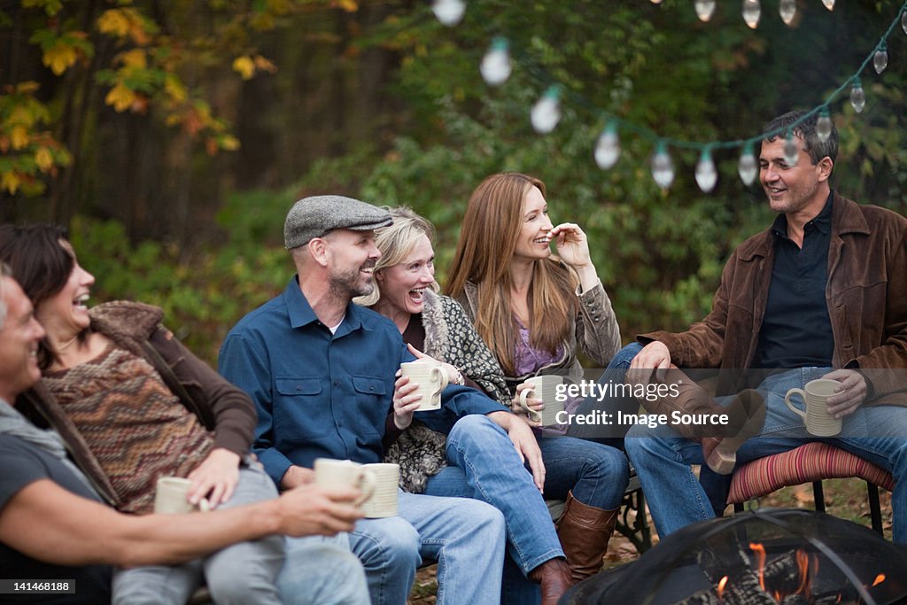 Smiling friends outdoors by fire