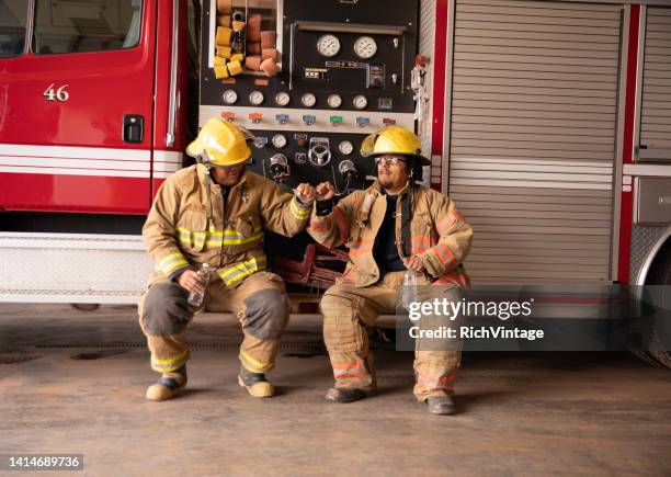 two firefighters in fire station - fire fighting stock pictures, royalty-free photos & images