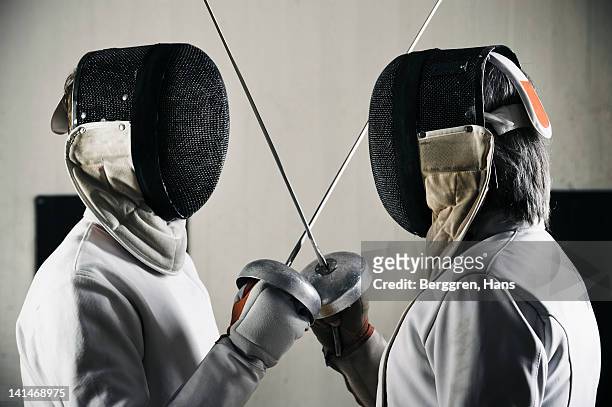 two fencers face to face in sports hall - rivalry stockfoto's en -beelden
