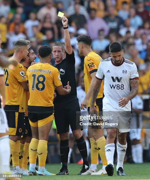 Morgan Gibbs-White of Wolverhampton Wanderers is shown the yellow card by referee John Brooks as Aleksandar Mitrovic walks away during the Premier...