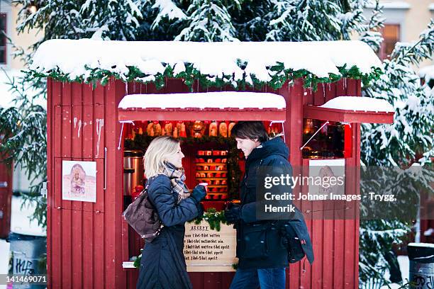 couple standing in front of food stall in snow - stockholm winter stock pictures, royalty-free photos & images