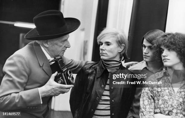 British fashion photographer Cecil Beaton talks with American pop artist Andy Warhol and twin brothers Jed and Jay Johnson as he takes photographs in...