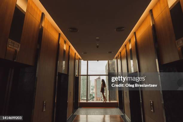 abstract photo of luxury hotel with unrecognizable woman silhouette near window with view of skyscrapers - abstract geometric silhouette woman stock pictures, royalty-free photos & images