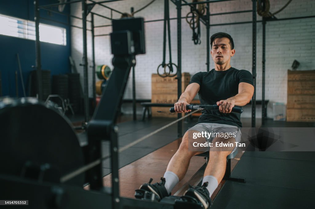 Asian Chinese Gay man exercising on rowing machine in a gym