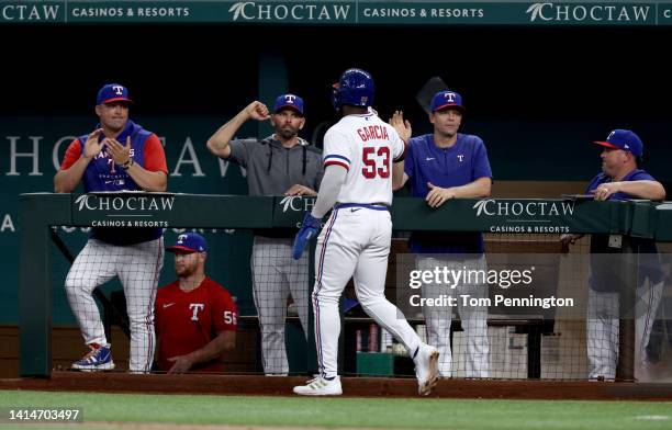 Adolis Garcia of the Texas Rangers celebrates with Manager Chris Woodward of the Texas Rangers after scoring on a RBI double hit by Jonah Heim of the...